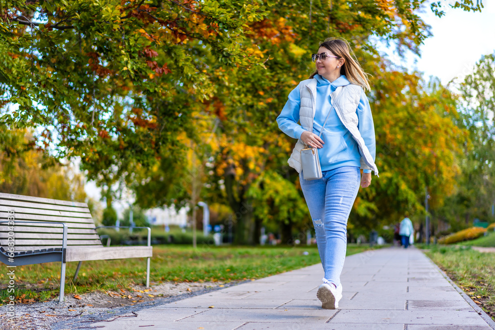 Fototapeta premium Healthy lifestyle - mid-adult woman walking in city park 