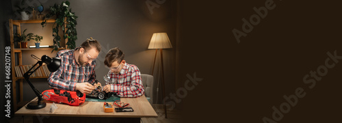 Father teaching his son for soldering and repair remote controlled car at home. Man and boy fixing broken toy. Copy space