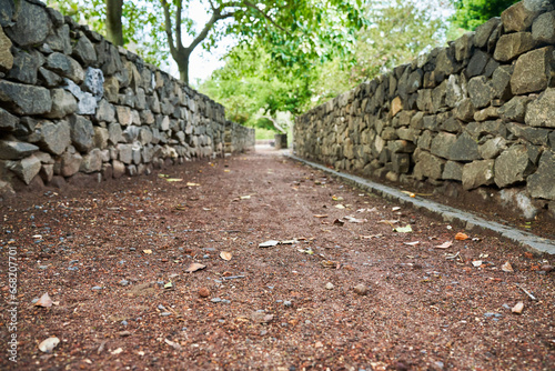 path framed by stone walls going into the distance with blurry greenery in the background