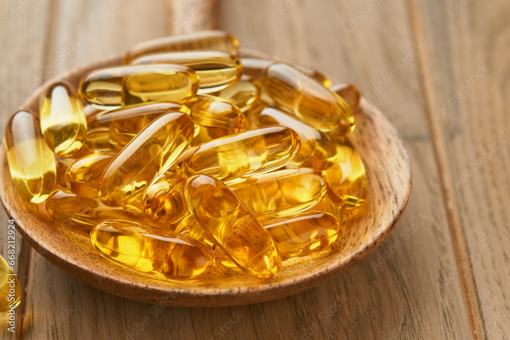 Close up capsules with Vitamin D, E or Omega 3,6,9 fatty acids in bottle on old wooden backgrounds. Food supplement oil filled fish oil. Natural supplements for healthy good life concept. Banner. Close up capsules with Vitamin D, E or Omega 3,6,9 fatty acids in bottle on old wooden backgrounds. Food supplement oil filled fish oil. Natural supplements for healthy good life concept. Banner.