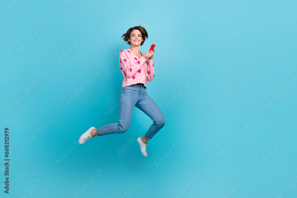 Full body photo of jumping overjoyed positive girl shopaholic enjoy order clothes online commerce advert isolated on blue color background