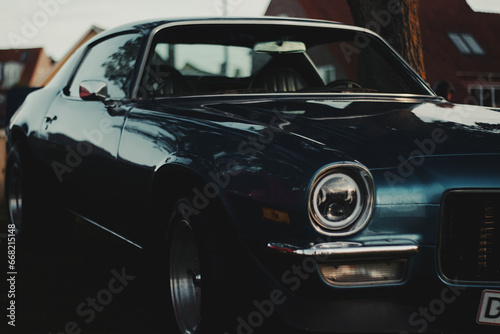 Vintage classic American car dark green, emerald color front side view with headlights, hood, wing on blurred background captured in Denmark  photo