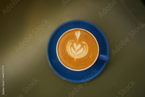 Hot coffee latte with latte art milk foam in cup mug on wood desk on top view. As breakfast In a coffee shop at the cafe,during business work concept,vintage style