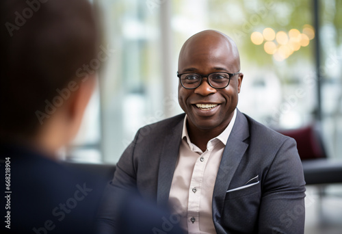 A 40s year old Afro male financial advisor in bald head with glasses counseling a woman in modern office setting natural lighting at day time