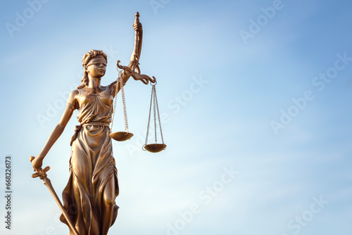 Legal law concept statue of Lady Justice with scales of justice with blue sky background