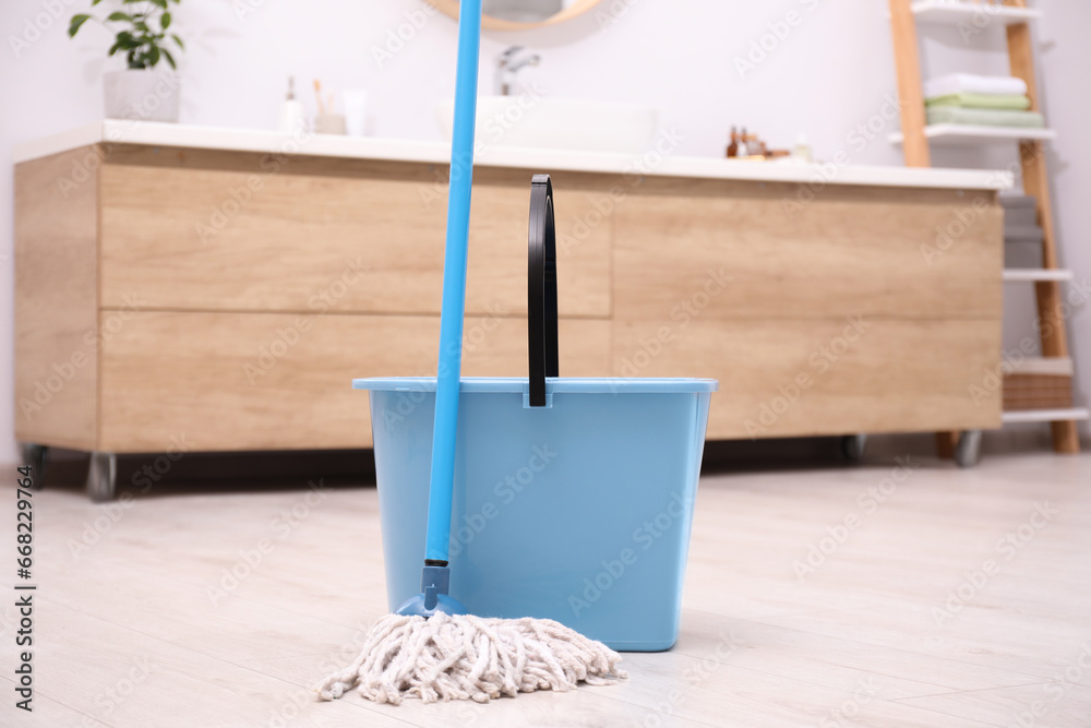 Mop and plastic bucket in bathroom. Cleaning floor - obrazy, fototapety, plakaty 