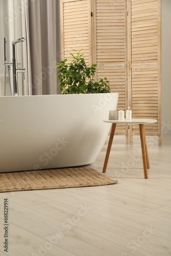 Fototapeta Naklejka Na Ścianę i Meble -  Spa day. Stylish bathroom with ceramic tub, houseplant and wooden side table