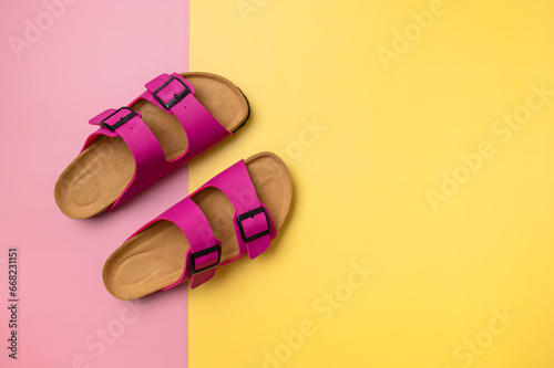Leather pink magenta sandals birkenstocks on pink and yellow background top view flat lay. Trendy fashion footwear mockup. Unisex summer shoes, genuine leather flip flops for vacation, beach photo