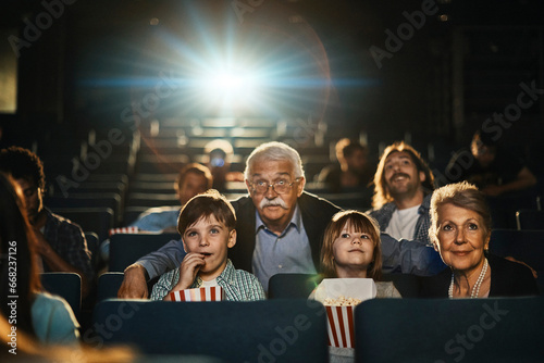 Multi-generational family engrossed in a captivating movie at the theater photo