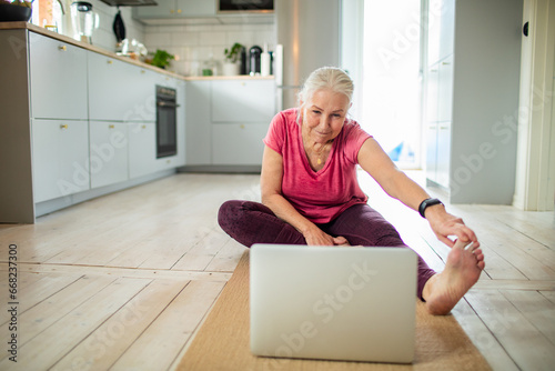 Senior woman staying active with an online yoga class at home photo