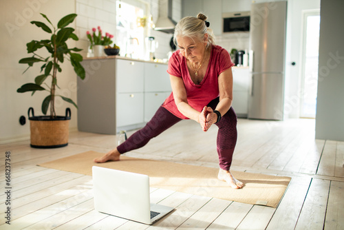 Senior woman staying active with an online yoga class at home photo