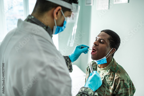 A healthcare worker performs a throat swab on a male soldier photo