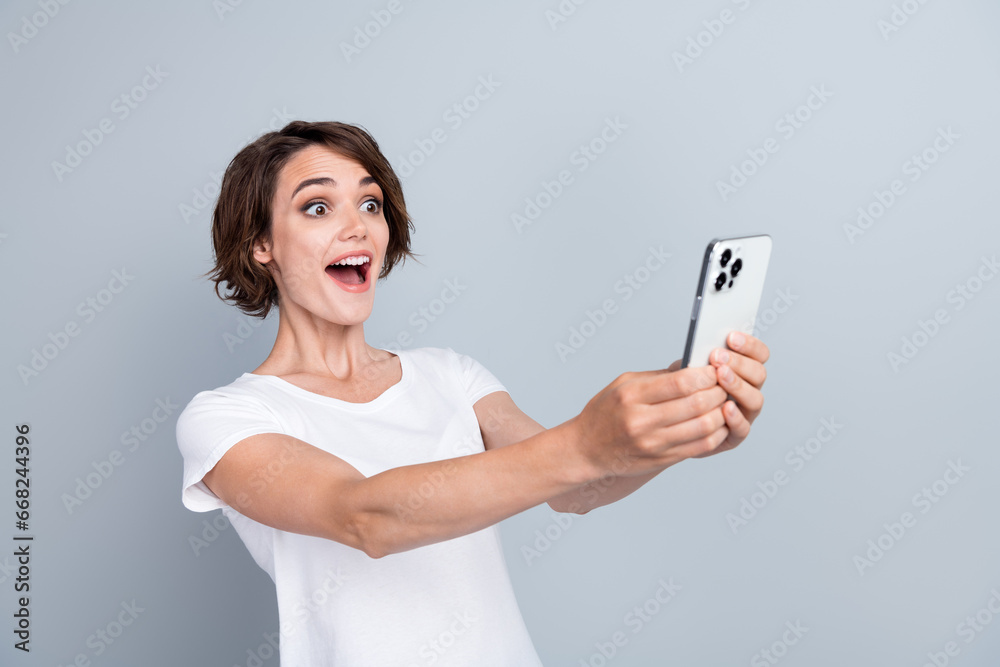 Photo of astonished funky lady open mouth hands hold smart phone surfing isolated on grey color background