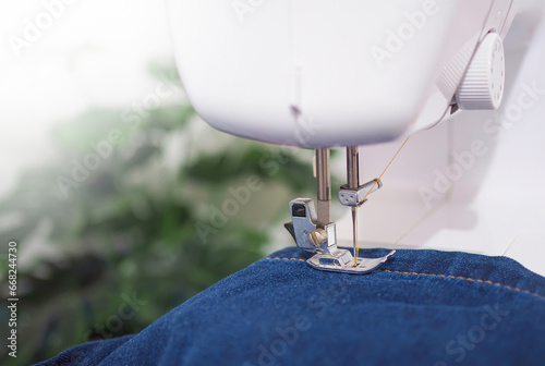 Close up sewing machine sew seam of blue denim jean. photo