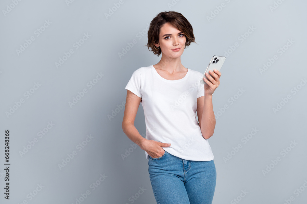 Portrait of stunning nice lady put hand pocket hold smart phone empty space isolated on grey color background Portrait of stunning nice lady put hand pocket hold smart phone empty space isolated on grey color background