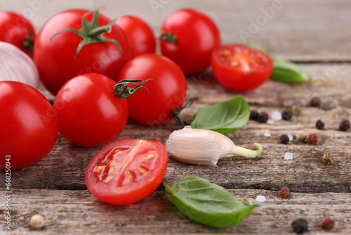 Ripe tomatoes, basil, garlic and spices on wooden table, closeup