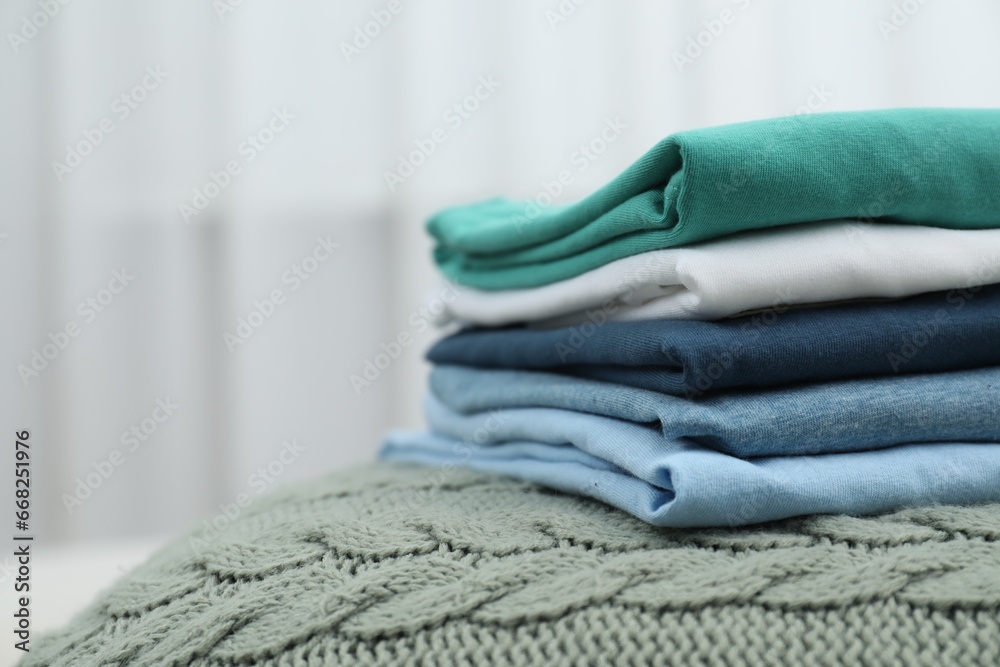 Sorting and organizing. Stack of different folded clothes on bed indoors, space for text Sorting and organizing. Stack of different folded clothes on bed indoors, space for text
