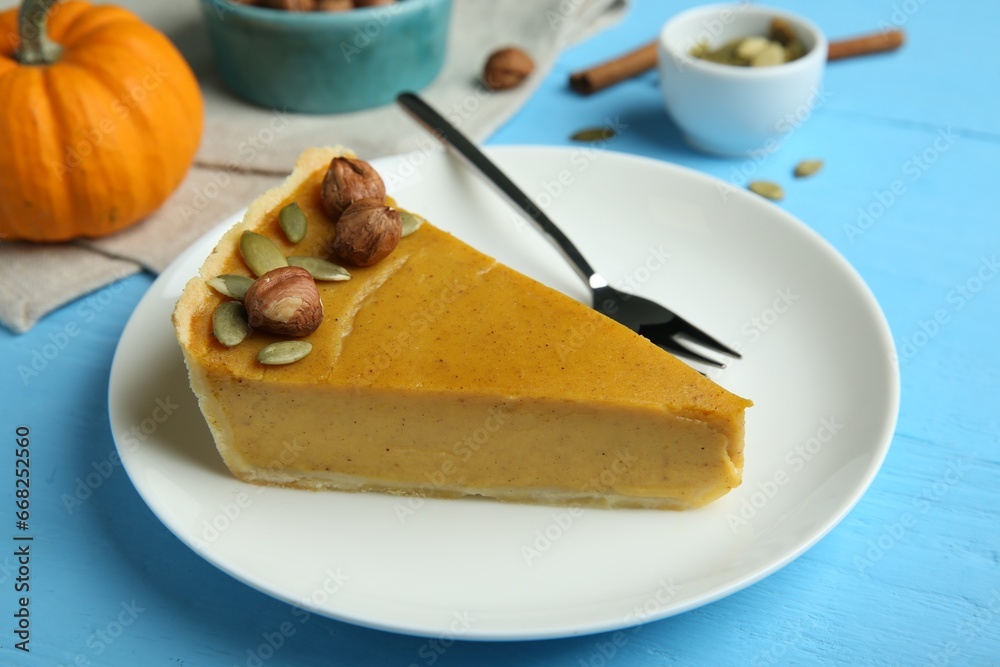 Piece of delicious pumpkin pie with hazelnuts, seeds and fork on light blue wooden table Piece of delicious pumpkin pie with hazelnuts, seeds and fork on light blue wooden table