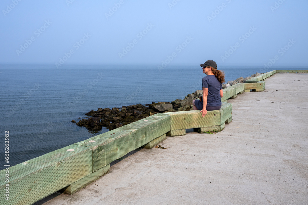 A woman looking at the sea from a wharf