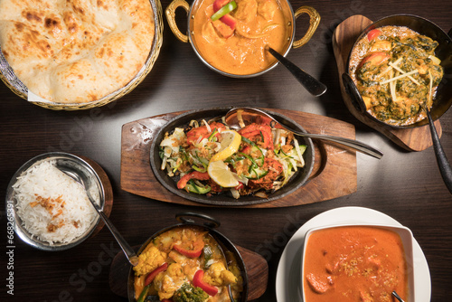 A presentation of different Indian dishes with Chicken Tikka Sizzlar in the middle with rice and nan bread.