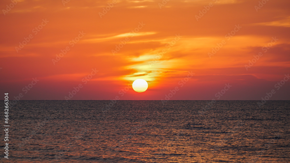 Bright sunset with large yellow sun under the sea surface, Panorama of sea sunset, seascape. Sunset over the sea horizon