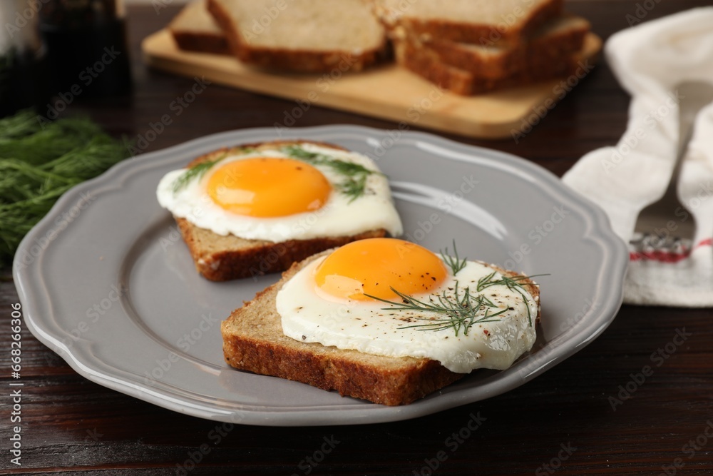 Plate with tasty fried eggs, slices of bread and dill on dark wooden table, closeup Plate with tasty fried eggs, slices of bread and dill on dark wooden table, closeup