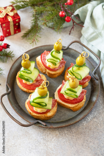 Creative appetizers christmas. Christmas tree canapes of salami, cheese, olives, tomatoes and cucumbers on a baguette. Copy space.