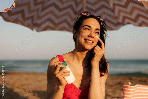 Woman using sunscreen cream. Beautiful woman with sun protection cream. Girl enjoy at the beach. photo
