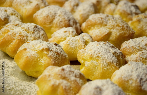 Süße Profiteroles, Windbeutel mit Zucker und Vanillecreme, Leckerei und Süßspeise, Nachspeise als Dessert, Hintergrund 