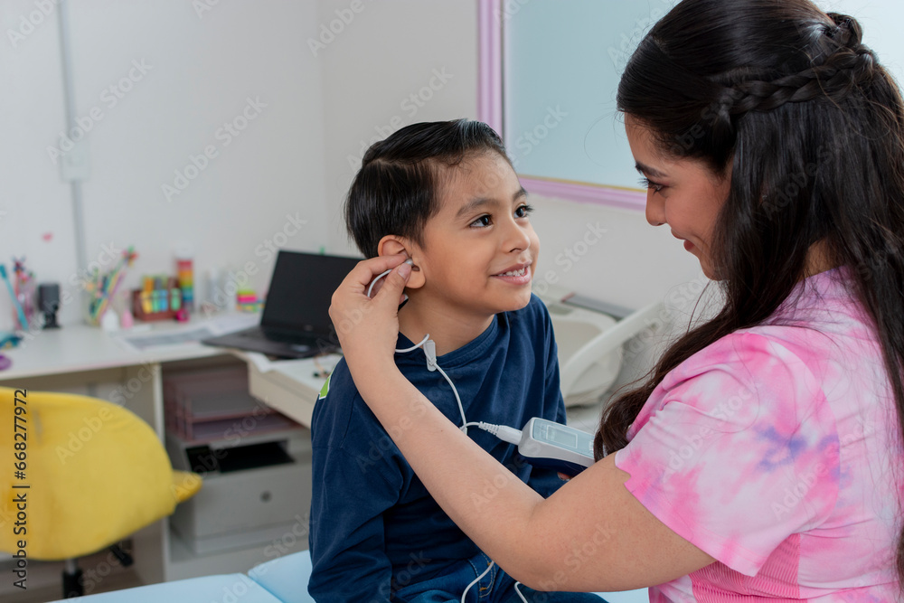 Nurse placing a headset on a child to perform a hearing test in the pediatric clinic, with copy space Nurse placing a headset on a child to perform a hearing test in the pediatric clinic, with copy space