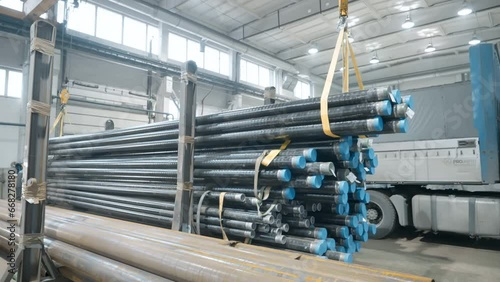 Huge amount of steel pipes loaded on the industrial factory crane machine. Lots of metal pipes manufactured at the industrial factory. Lifting up stacks of pipes made at industrial factory photo