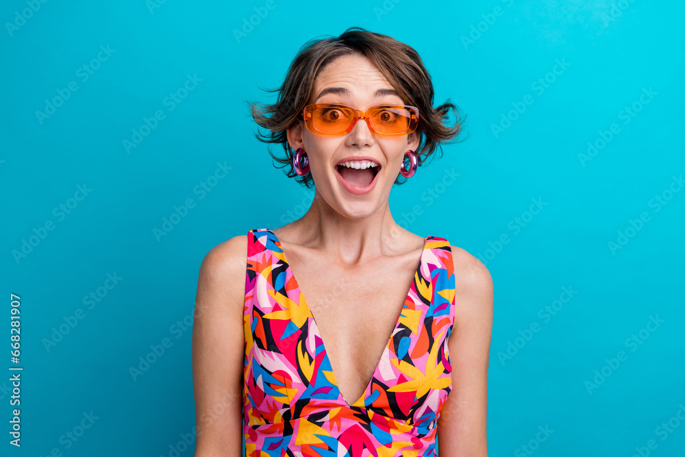 Portrait of impressed ecstatic person with bob hairdo wear colorful dress sunglass staring at sale isolated on blue color background Portrait of impressed ecstatic person with bob hairdo wear colorful dress sunglass staring at sale isolated on blue color background