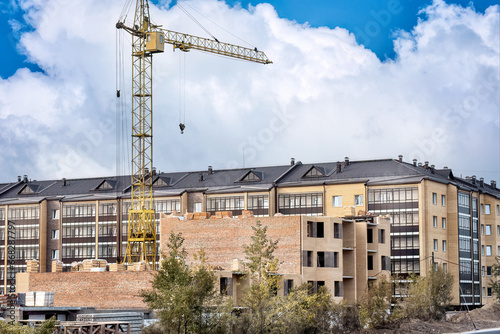 A construction site of a many-storied building with a lifting crane.