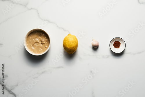Tarator - Lebanese sauce from tahini with garlic, lemon juice and water. White or cream colored sauce in a jar on a marble background