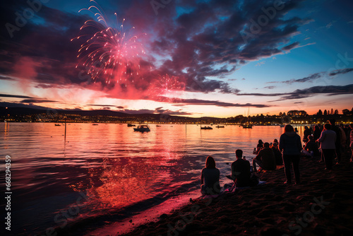 Spectators gather at the lakeside to watch vibrant fireworks illuminate the evening sky, reflecting beautifully on the water.