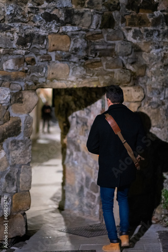 An unrecognizable young Latino with his back to us crossing a door in the wall.