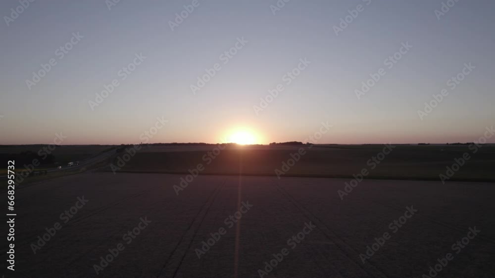 View of the sunset above the horizon and wheat fields, upward lateral drone movement View of the sunset above the horizon and wheat fields, upward lateral drone movement