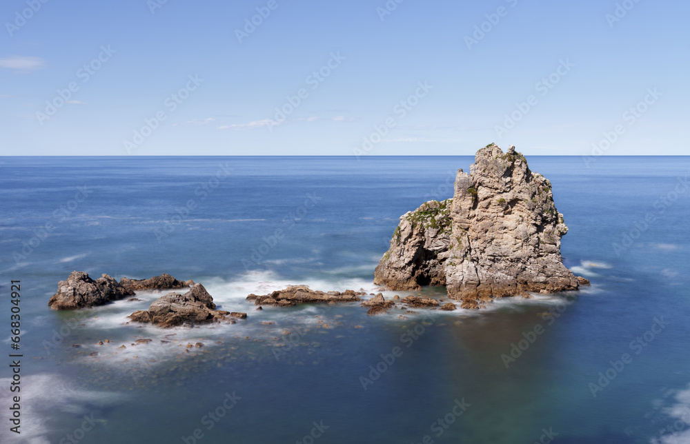 Rocks in the blue waters of the cantabric sea, pendueles beach in Asturias, Spain.