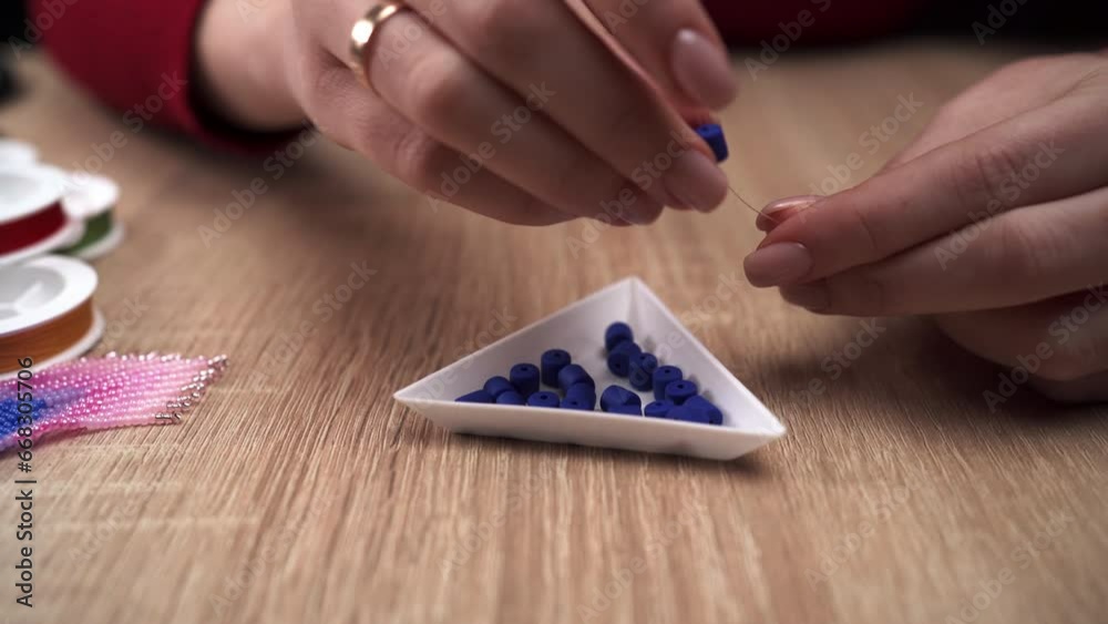 Beading concept. Woman making blue bead bracelet at home while sitting at table