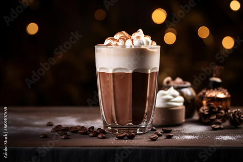 Hot chocolate in a glass cup topped with whipped cream over bokeh background, copy space. Cozy hot drink consisting of grated or melted chocolate or cocoa powder, warmed milk or water, and sweetener