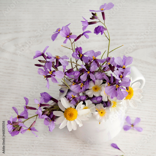 flores silvestres de color morado , en jarra de ceramica blanca 