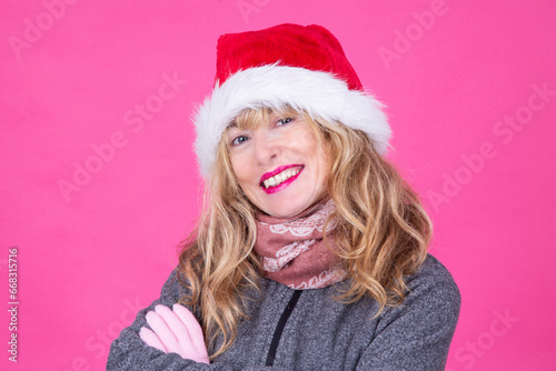 smiling woman wearing santa claus hat on pink background. holiday celebration concept
