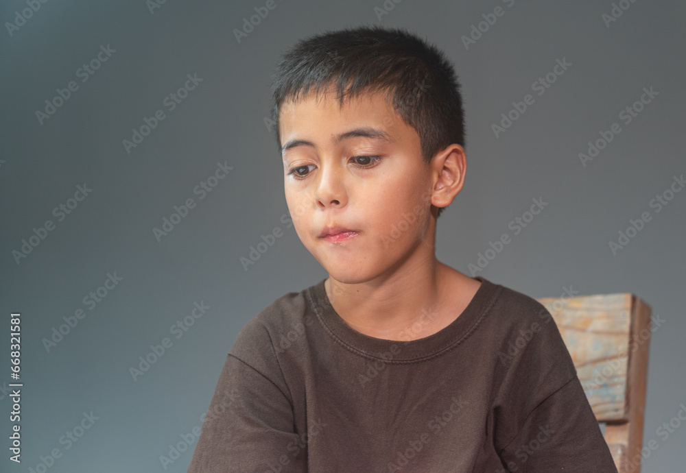 A boy loves a cell phone while eating popcorn with gusto..Boy staring at cell phone while eating popcorn..The boy happily sat and ate popcorn.