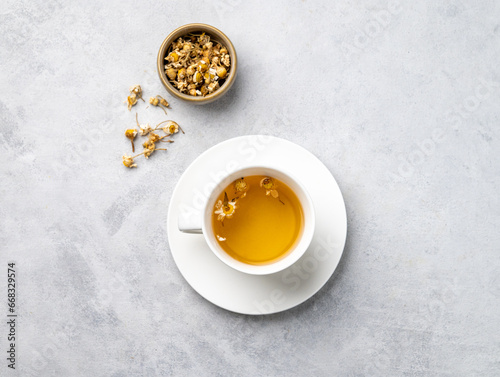 Chamomile herbal tea in a white cup on a light background with dry flowers. The concept of a healthy detox drink for health and sleep.