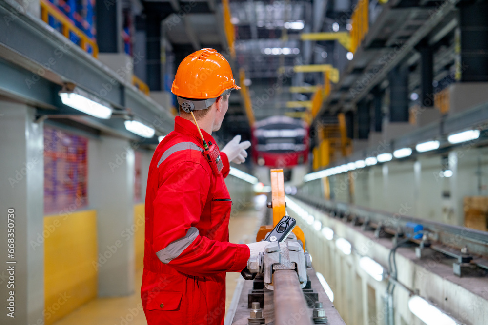 Back of professional technician worker with safety uniform point to the electrical or sky train in factory workplace. Back of professional technician worker with safety uniform point to the electrical or sky train in factory workplace.