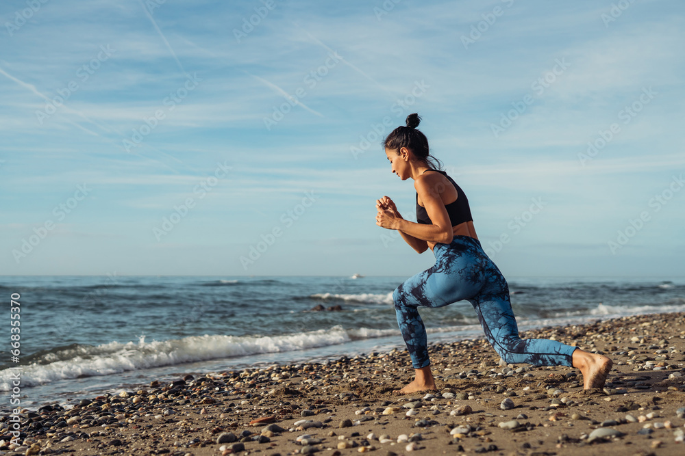 The girl is doing fitness on the seaside.