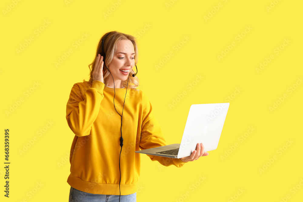 Female technical support agent with laptop on yellow background Female technical support agent with laptop on yellow background
