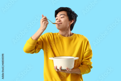 Young Asian man with spoon ...