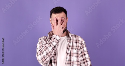 Portrait of bearded man making face palm hand gesture feeling shame and embarrassment on purple background. Emotion and people concept.