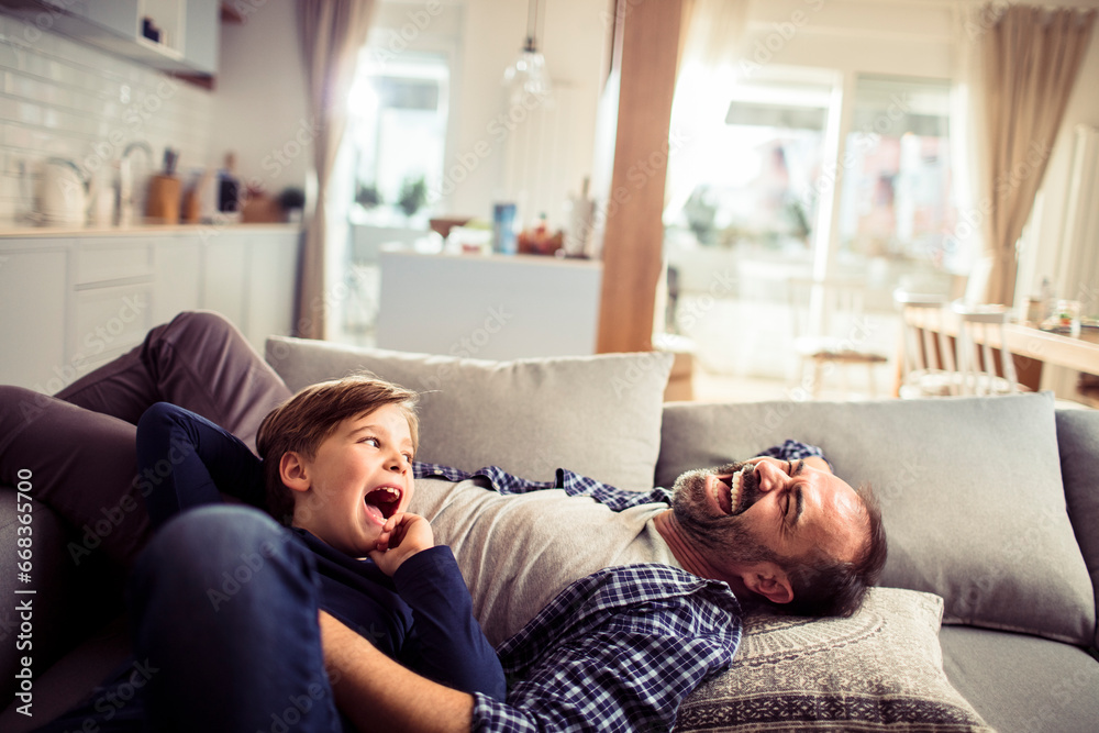 Happy young boy laying on the couch with his dad at home Happy young boy laying on the couch with his dad at home